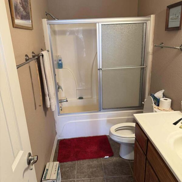 Dated bathroom with tub and sliding glass shower doors toilet wood vanity and tile floor