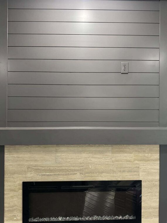 Gray shiplap accent wall above a tiled fireplace surround with a black linear electric fireplace insert