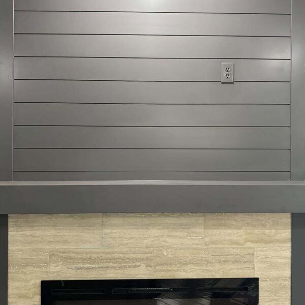 Gray shiplap accent wall above a tiled fireplace surround with a black linear electric fireplace insert