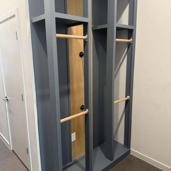 Custom blue gray built in locker unit with wood hanging rods against a wall near a door