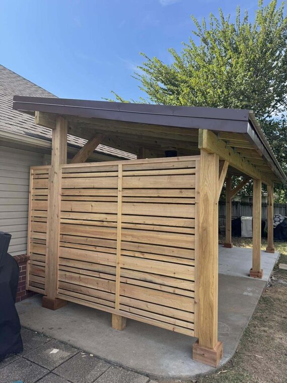 Wood patio cover with slatted privacy wall over a concrete pad beside a house