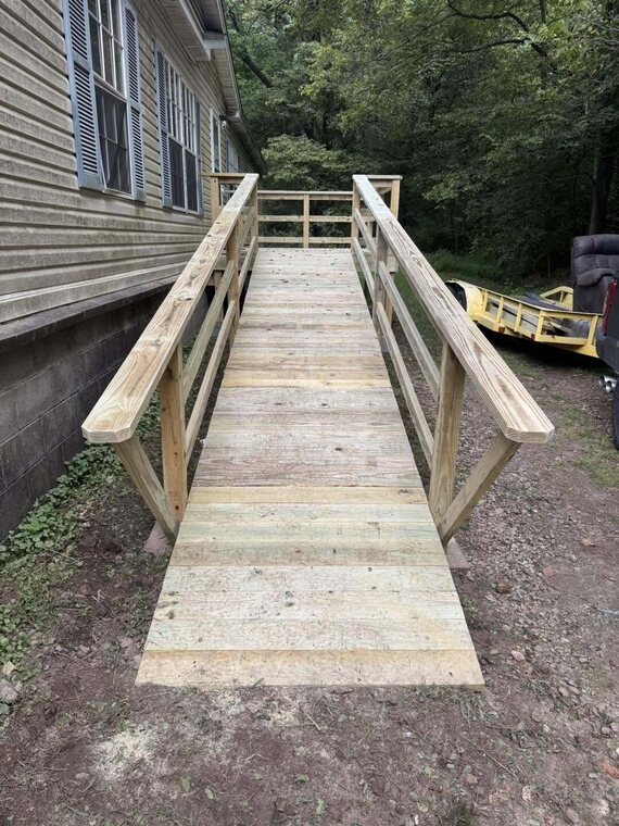New light wood accessibility ramp with handrails along the side of a house