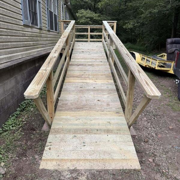 New light wood accessibility ramp with handrails along the side of a house
