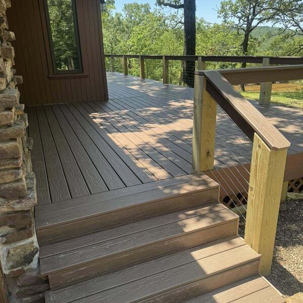 Finished composite deck with steps and a wood post cable railing overlooking wooded hills