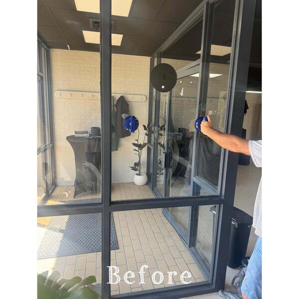 Worker using a suction cup tool to remove a large glass storefront door panel at an entryway