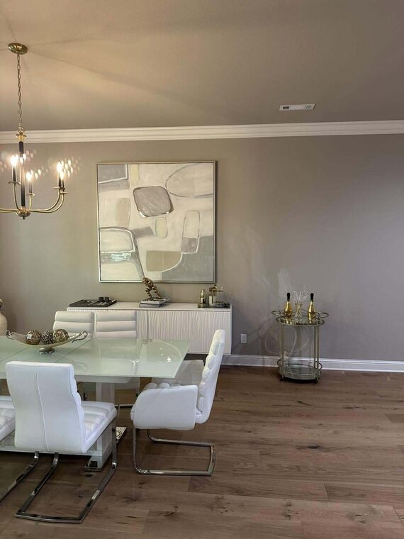 Dining room with wood flooring, gray walls, chandelier, white glass top table and chairs