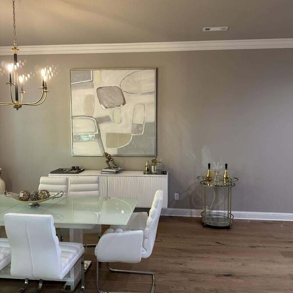 Dining room with wood flooring, gray walls, chandelier, white glass top table and chairs