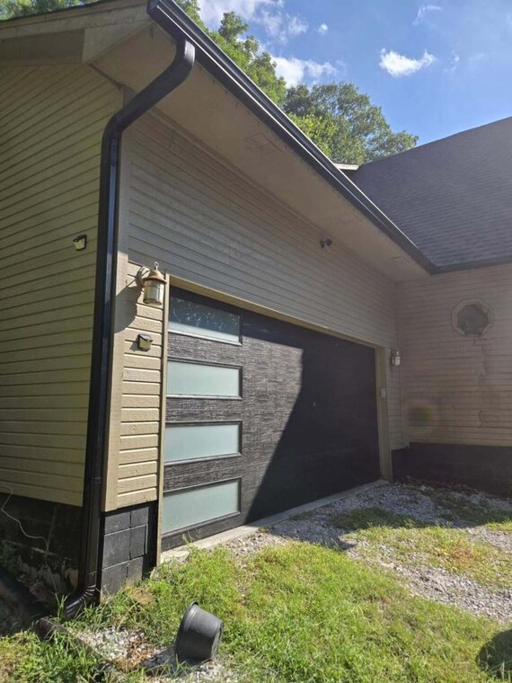 Exterior corner of a home with gutters, lap siding, and a garage door with frosted glass panels and dark center