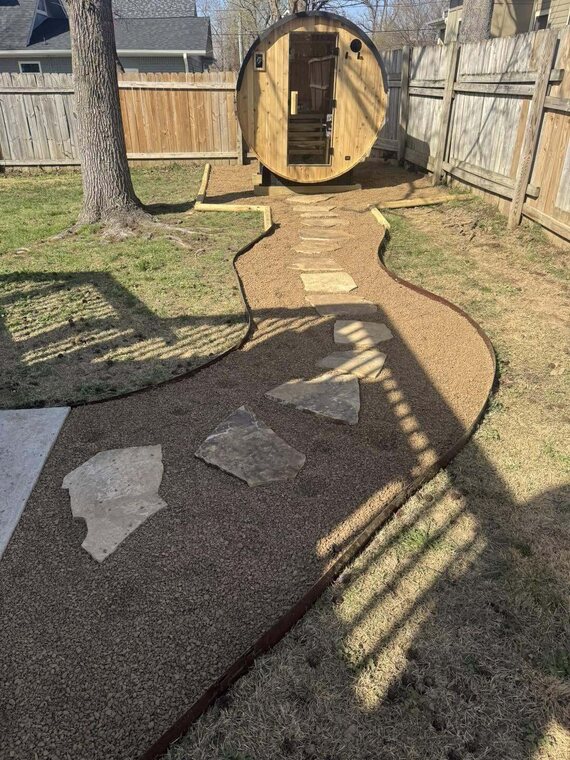 Backyard barrel sauna with curving gravel path and flagstone steppers along wood fence