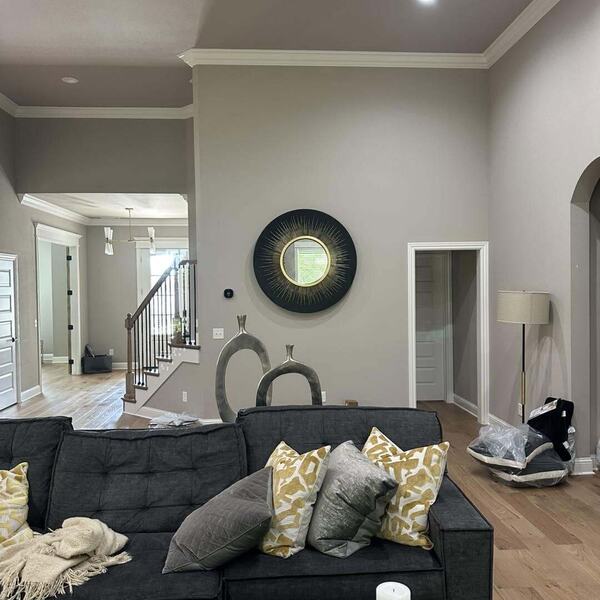Living room with gray painted walls crown molding a staircase and a dark charcoal sofa