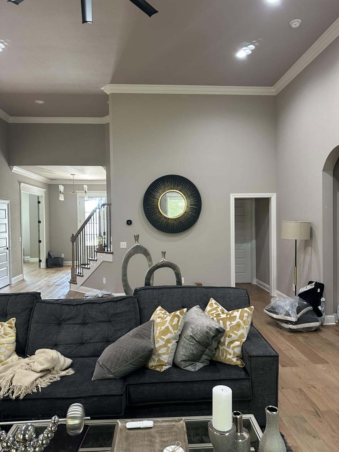 Living room with gray painted walls crown molding a staircase and a dark charcoal sofa