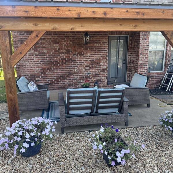 Covered wood patio over a concrete slab with wicker furniture against a brick home