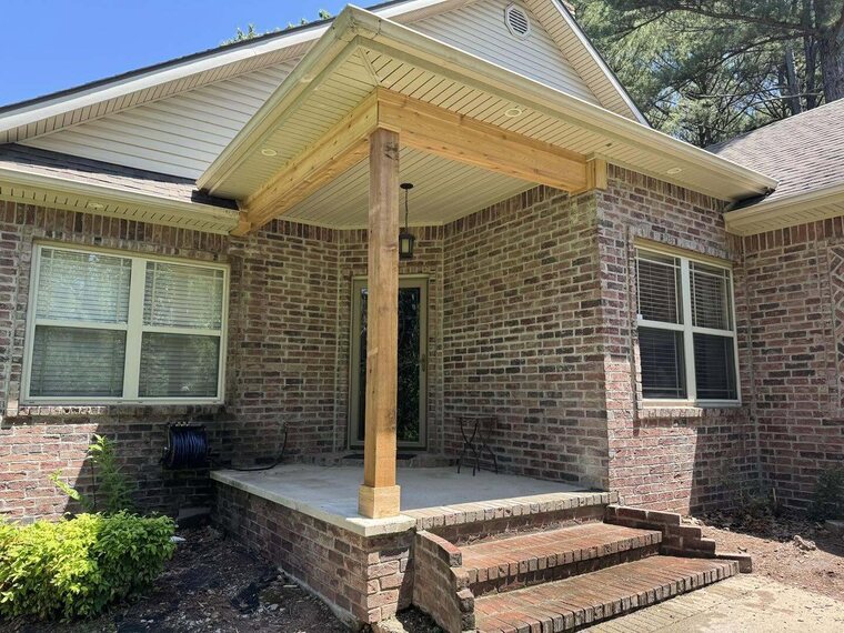 Brick home entry with a new gabled covered porch supported by a wood post over a concrete slab