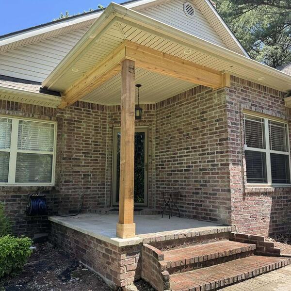 Brick home entry with a new gabled covered porch supported by a wood post over a concrete slab