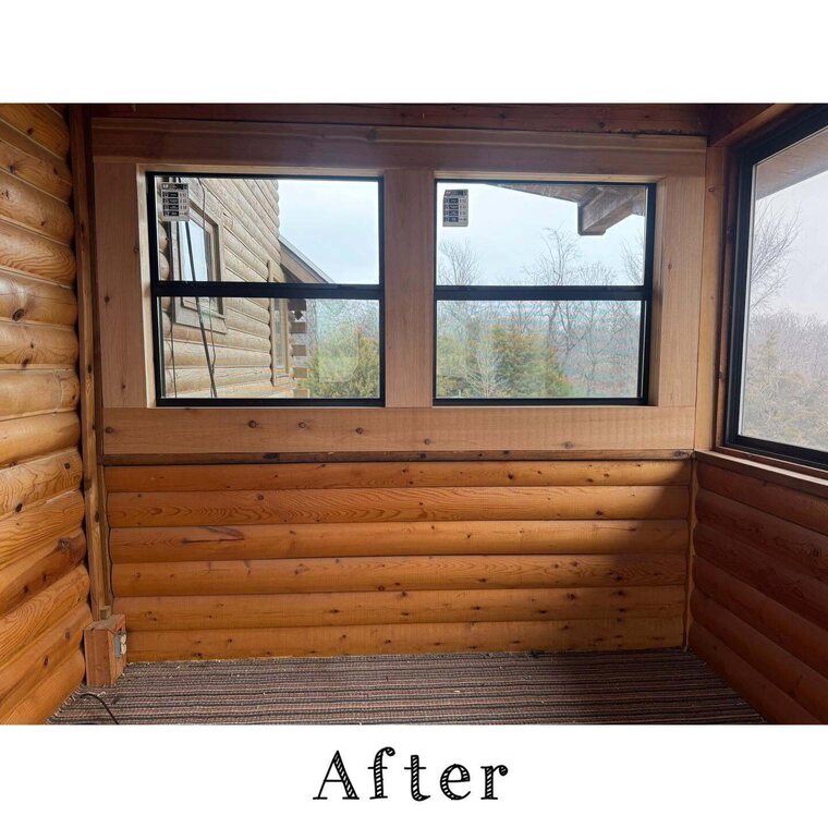 Interior corner of an enclosed sunroom with log style wood walls and windows looking out at bare trees