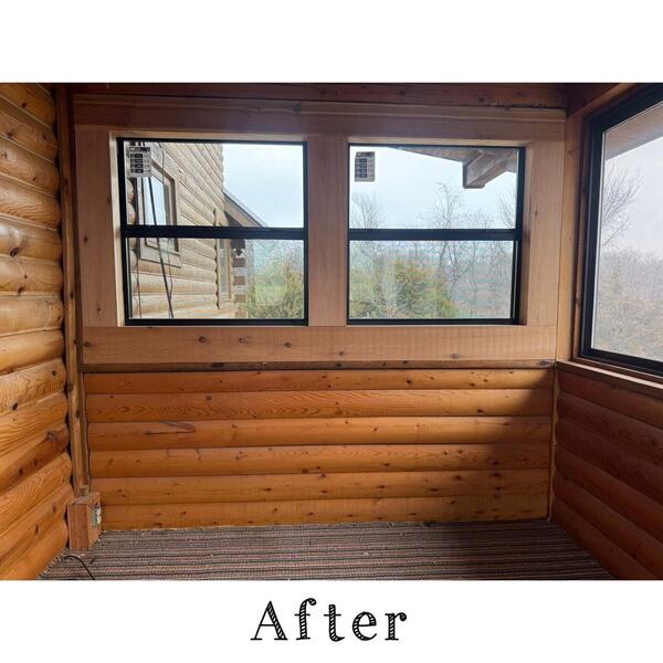 Interior corner of an enclosed sunroom with log style wood walls and windows looking out at bare trees
