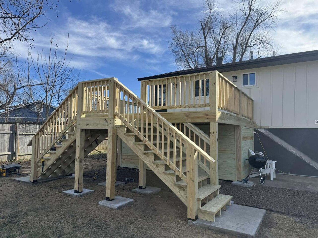A solid new pressure treated deck with a staircase and under deck storage on the same home