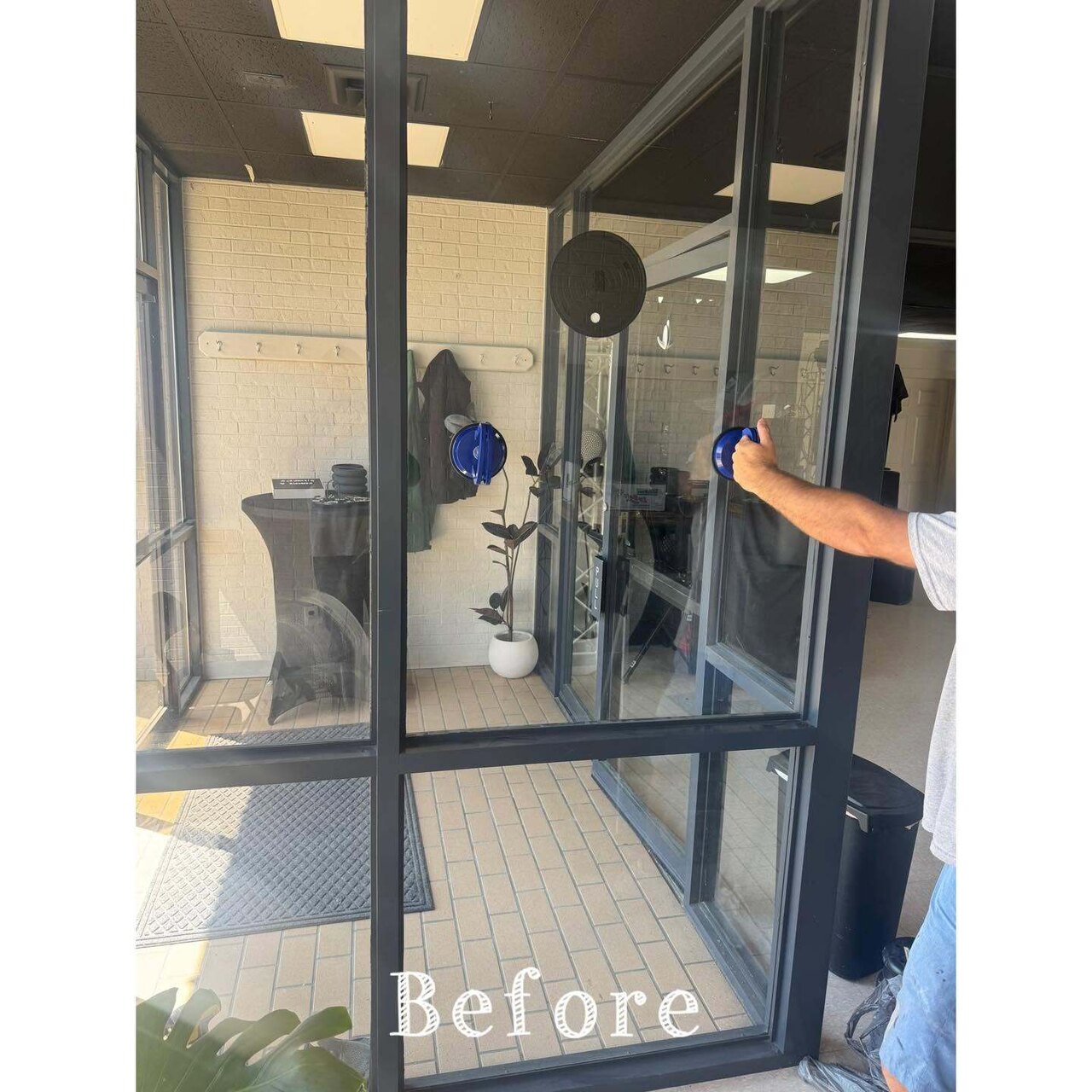 A worker pulling the old failing glass from a commercial storefront entry with suction cups